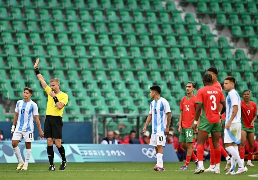 L'arbitre suédois Glenn Nyberg (2e à gauche) siffle le coup de sifflet final alors que les joueurs de l'Argentine (à droite) et du Maroc se préparent à reprendre le jeu dans un stade vide après des incidents, une interruption de deux heures et l'annulation du but égalisateur de l'Argentine, lors du match de football du groupe B masculin entre l'Argentine et le Maroc lors des Jeux Olympiques de Paris 2024 au stade Geoffroy-Guichard à Saint-Etienne le 24 juillet 2024. (Photo par Arnaud FINISTRE / AFP)