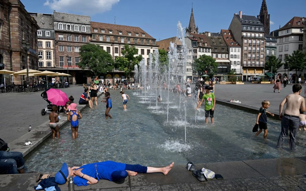 People cool off with water fountains in Strasbourg, eastern France, as a heat wave hits France on July 11, 2023. For the third month running, around two-thirds of France's water tables remain below seasonal normals, fuelling drought and threatening water supplies. A situation that is unlikely to improve as the summer heat settles over the country. (Photo by FREDERICK FLORIN / AFP) (Photo by FREDERICK FLORIN/AFP via Getty Images)