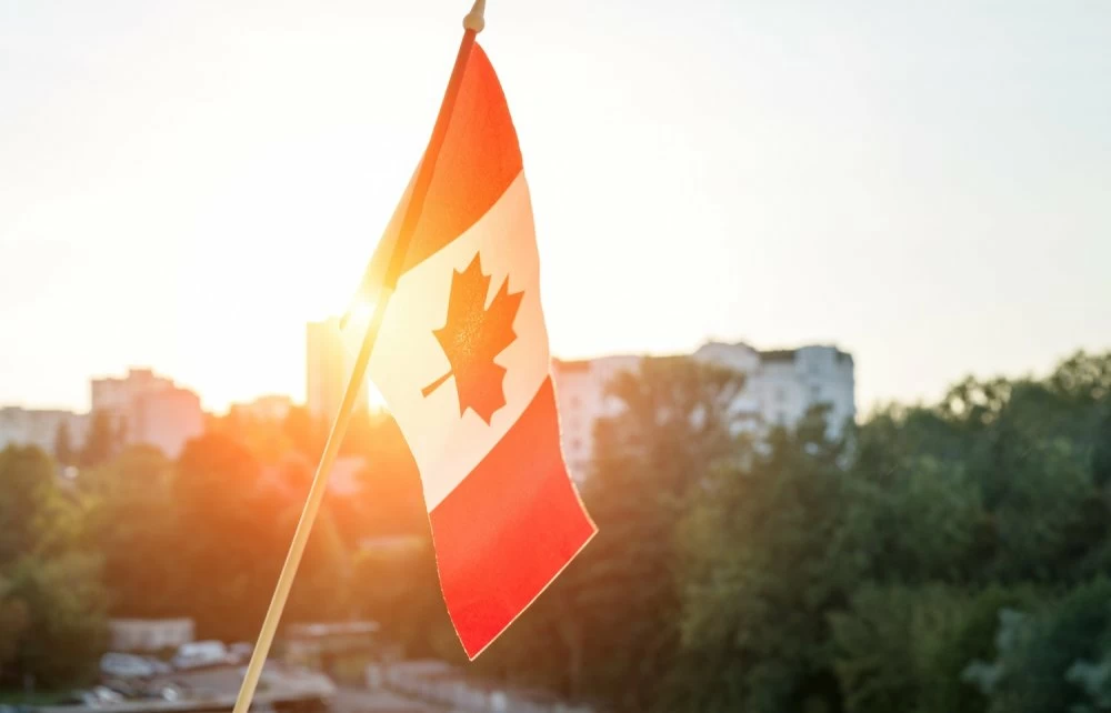 Flag of Canada from window on sunset background