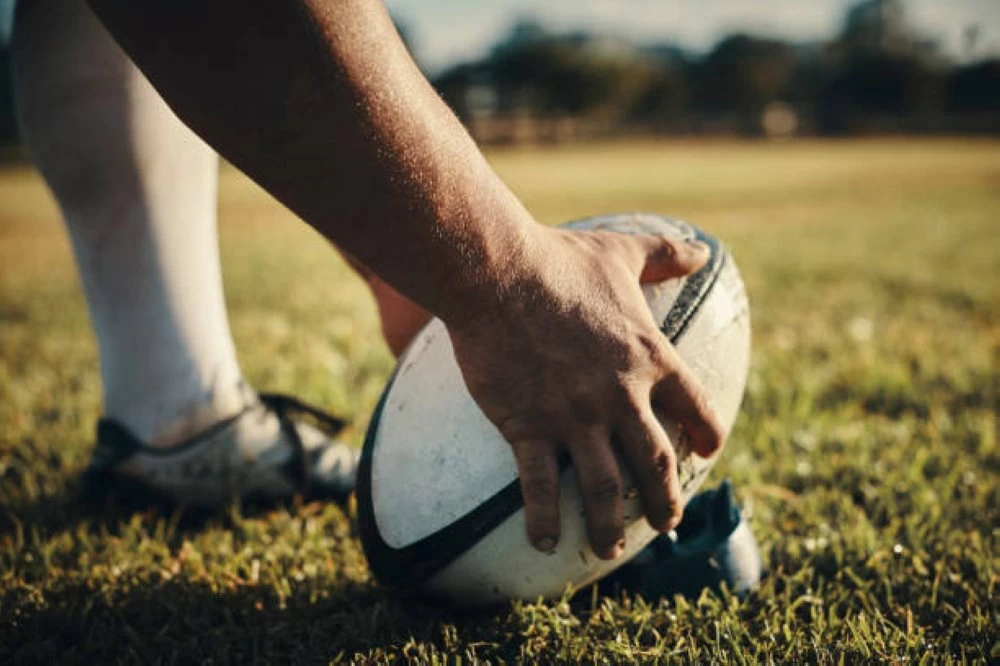 Cropped shot of an unrecognizable rugby player preparing for a kick on the field during the day