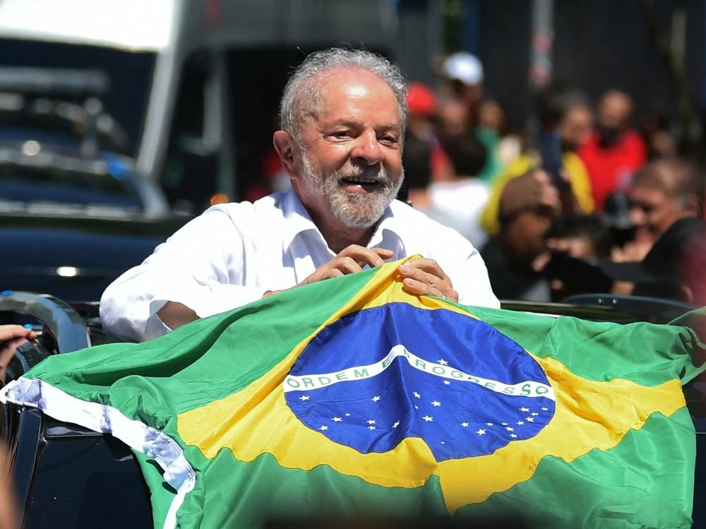 TOPSHOT - Brazilian former President (2003-2010) and candidate for the leftist Workers Party (PT) Luiz Inacio Lula da Silva holds a Brazilian flag while leaving a polling station during the presidential run-off election, in Sao Paulo, Brazil, on October 30, 2022. - After a bitterly divisive campaign and inconclusive first-round vote, Brazil elects its next president in a cliffhanger runoff between far-right incumbent Jair Bolsonaro and veteran leftist Luiz Inacio Lula da Silva. (Photo by CARL DE SOUZA / AFP) (Photo by CARL DE SOUZA/AFP via Getty Images)